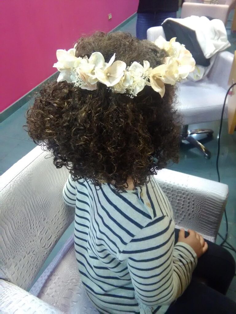 Peinado infantil con rizos naturales y adorno floral
