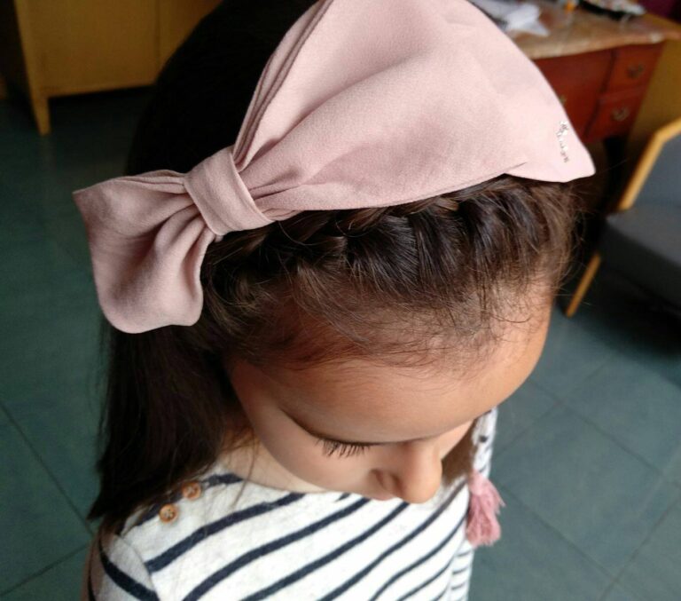 Peinado infantil con lazo rosa realizado en Peluquería Pilar Burbano